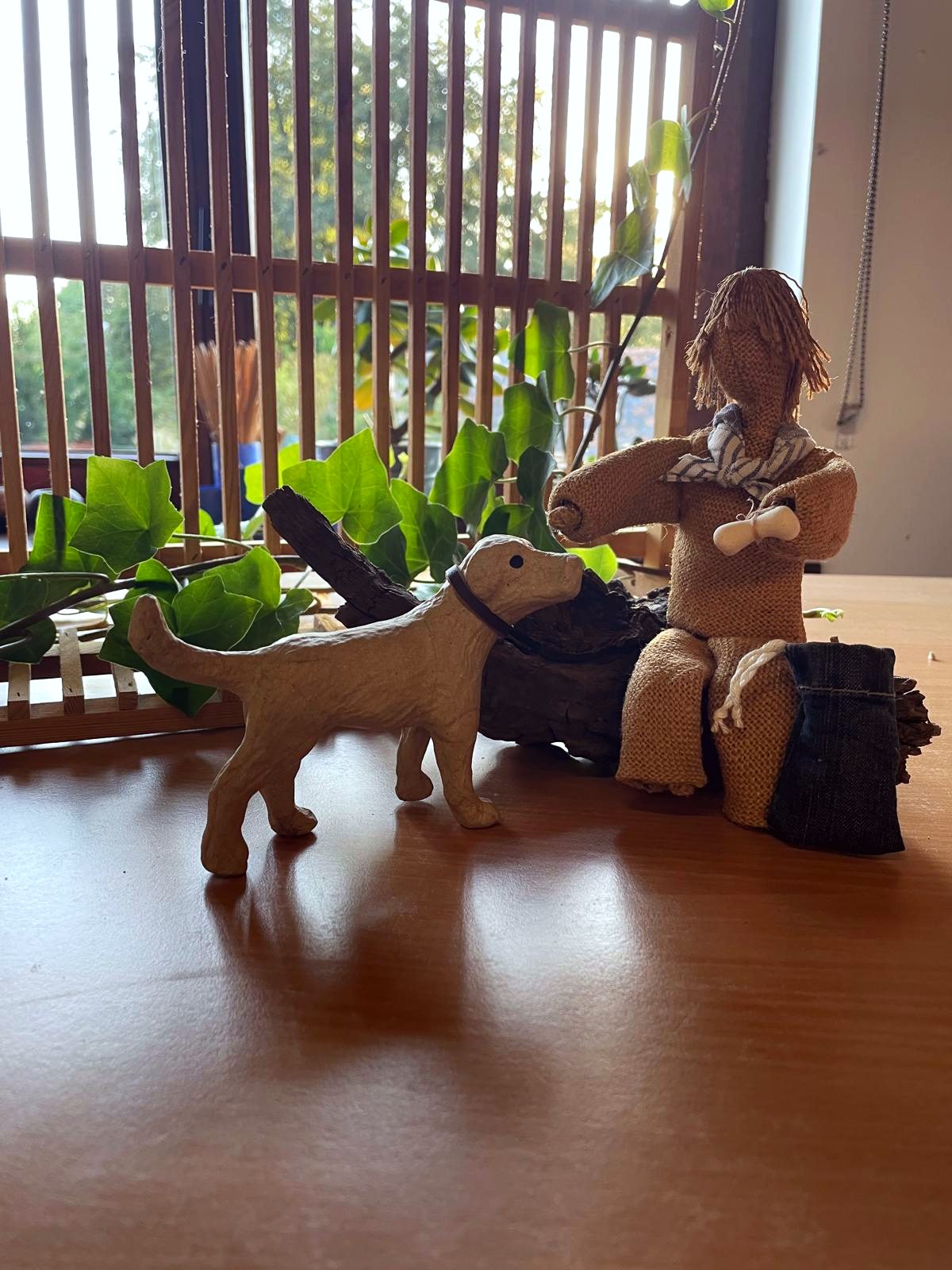 Figurine en toile de jute et chien en papier mâché devant la fenêtre de l'atelier